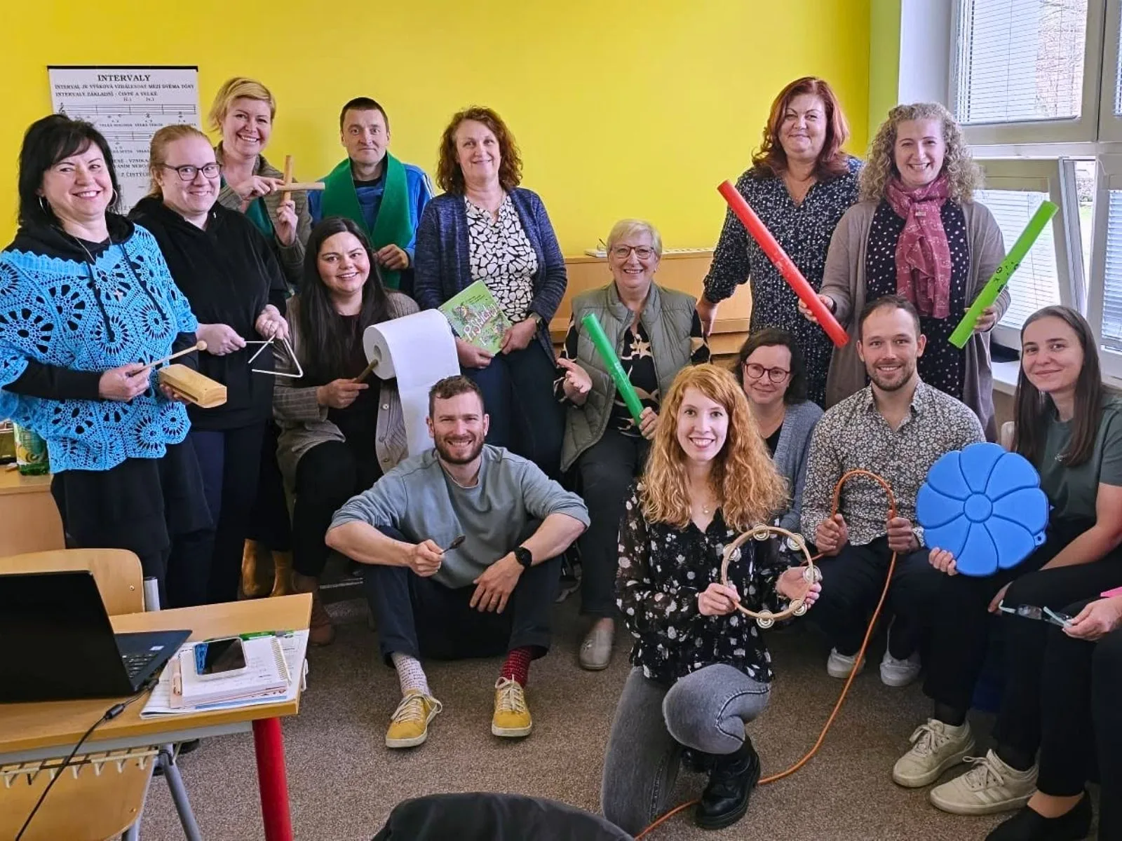 Skupina pedagogů společně pracuje s notovým materiálem u klavíru
